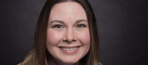 Corporate headshot against a medium gray background